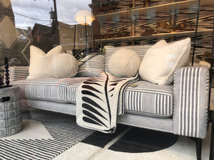 grey and white striped sofa with white pillows and throw blanket